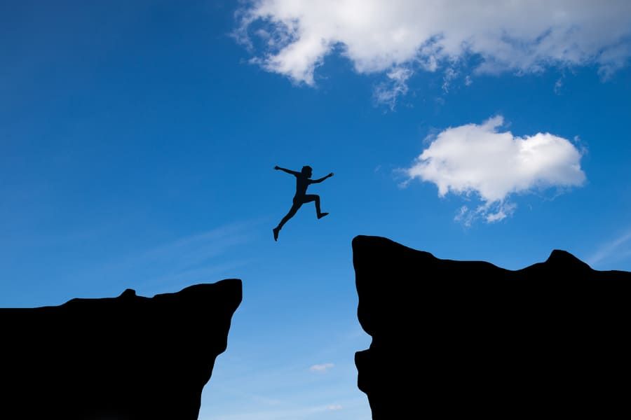 man jump through gap hill man jumping cliff sunset background business concept idea