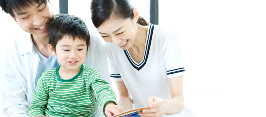 a young child reading a book with his parents