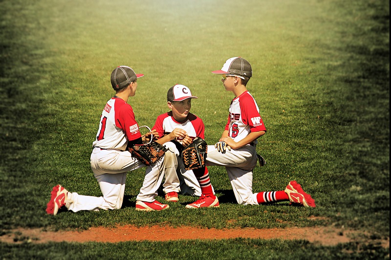 Photo of 3 baseball players kneeling and talking