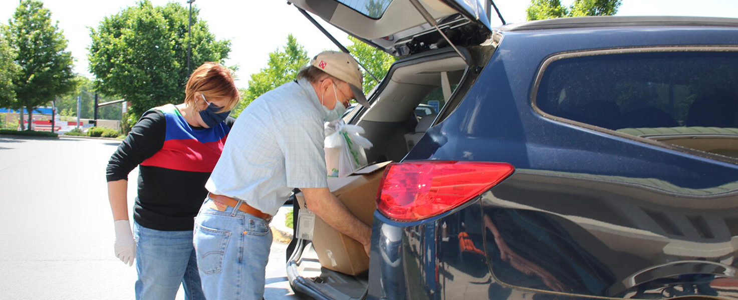 man putting box in car