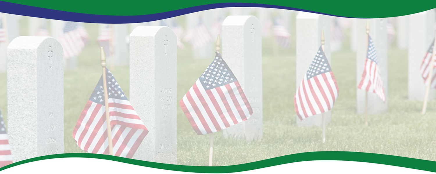photograph of a row of white headstones with American flags displayed in front of each