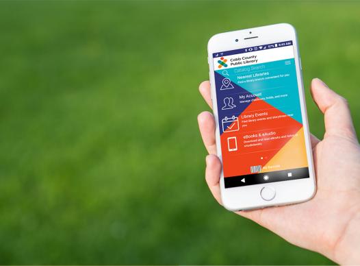 close up of a hand holding a phone with open to a screen of the Cobb Library app