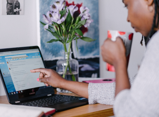woman drinking coffee while browsing on a laptop