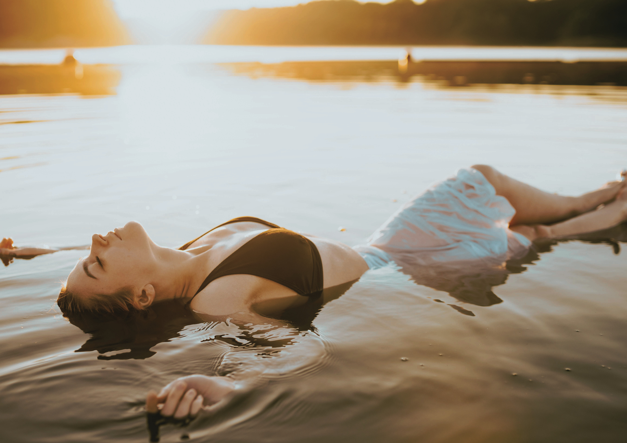 Femme allongée et flottant dans l’eau, symbole de réception corporelle et de détente profonde sans effort.
