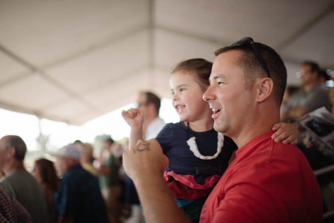 Dad and child cheering on a sports team in candid photo