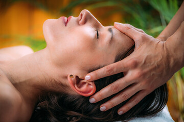 A woman with hands lightly placed on her head receiving craniosacral therapy