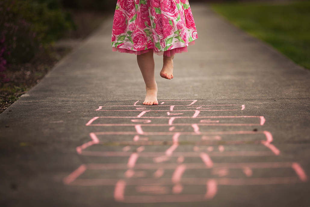 child playing hopscotch with sidewalk acting as a leading line