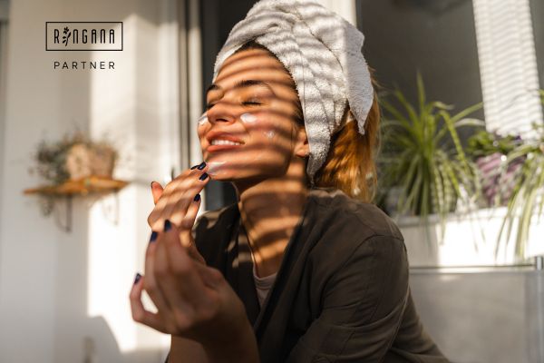 Hooggevoelige vrouw past zelfzorg toe met RINGANA’s 100% verse, vegan elixirs voor huidverzorging in een rustgevende omgeving.
