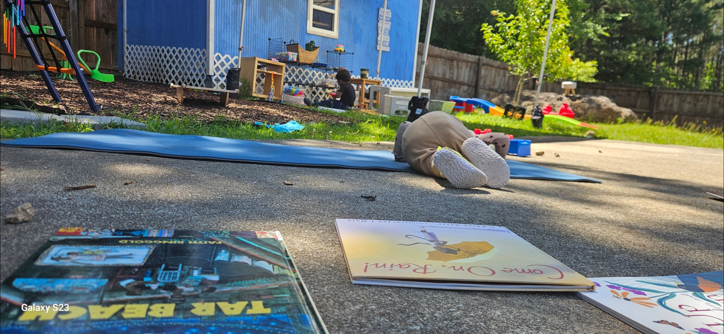 Our 18-month-old and 3-year-old lounging outside with books, showing what unschooling looks like in real life.