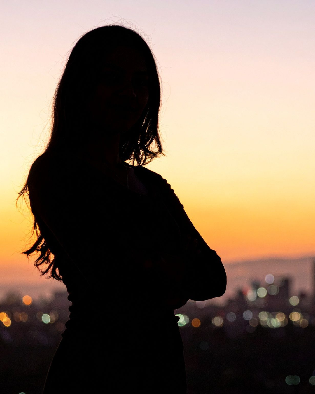 a silhouette of a woman staring out over a city 