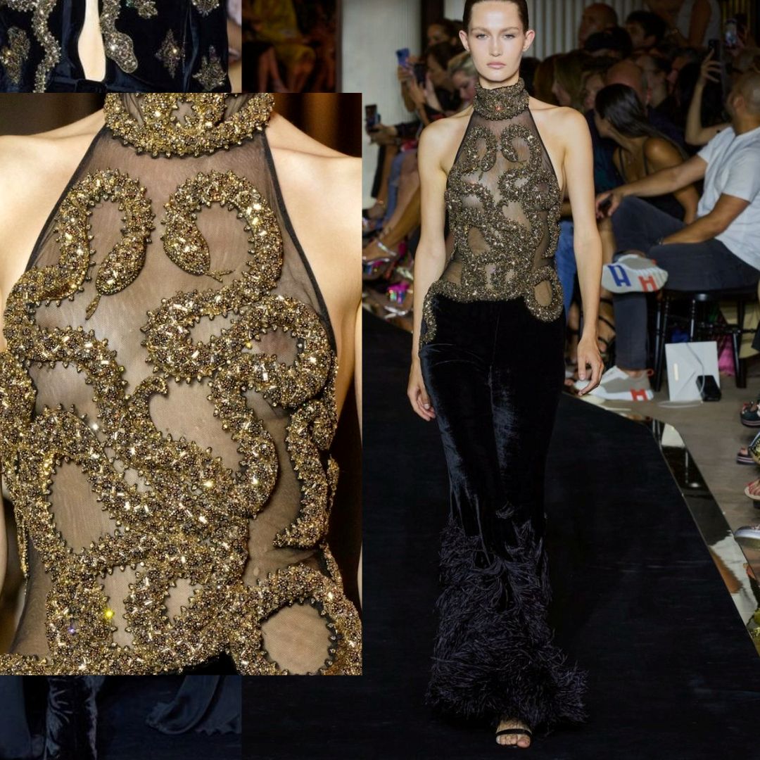 A stunning design from Zuhair Murad’s Fall 2022 Couture collection. The gown features intricate gold snake embellishments crafted from shimmering beadwork, forming a striking pattern over a sheer halter-neck bodice. The look is completed with a black velvet skirt accented by dramatic feathered details.