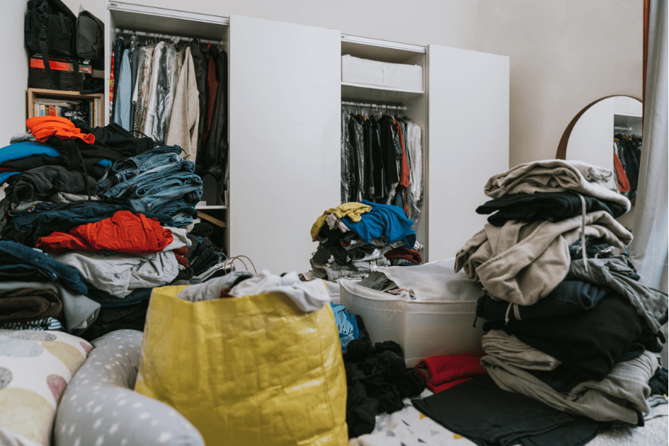 Accumulation de vêtements en désordre dans une chambre, illustrant la fatigue liée au bazar au quotidien.