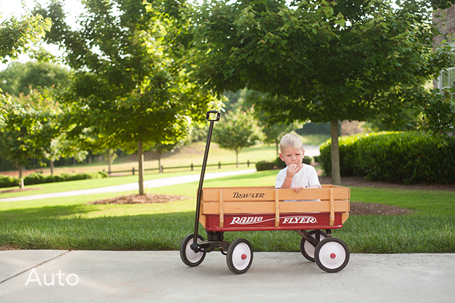 Child wearing a white shirt sitting in a wagon crying.