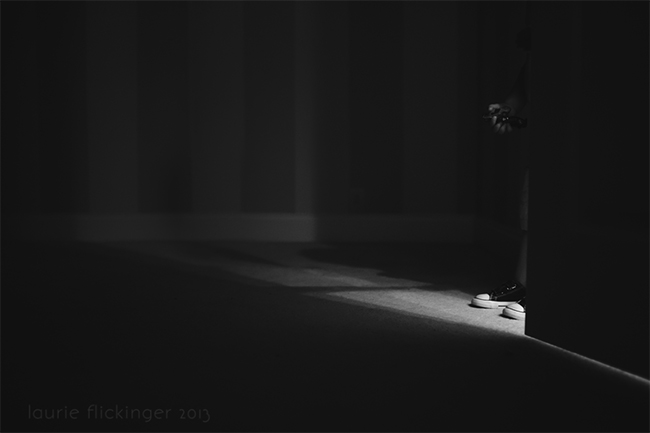 child shoes in light surrounded by shadows in low light room