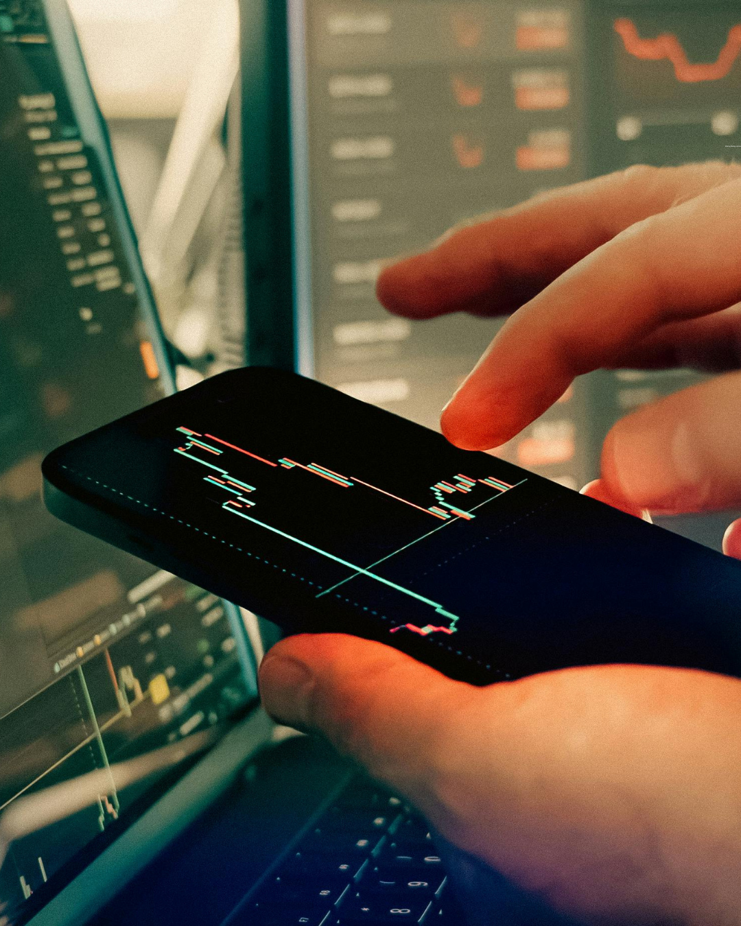 A hand holding a phone with charts on it. 