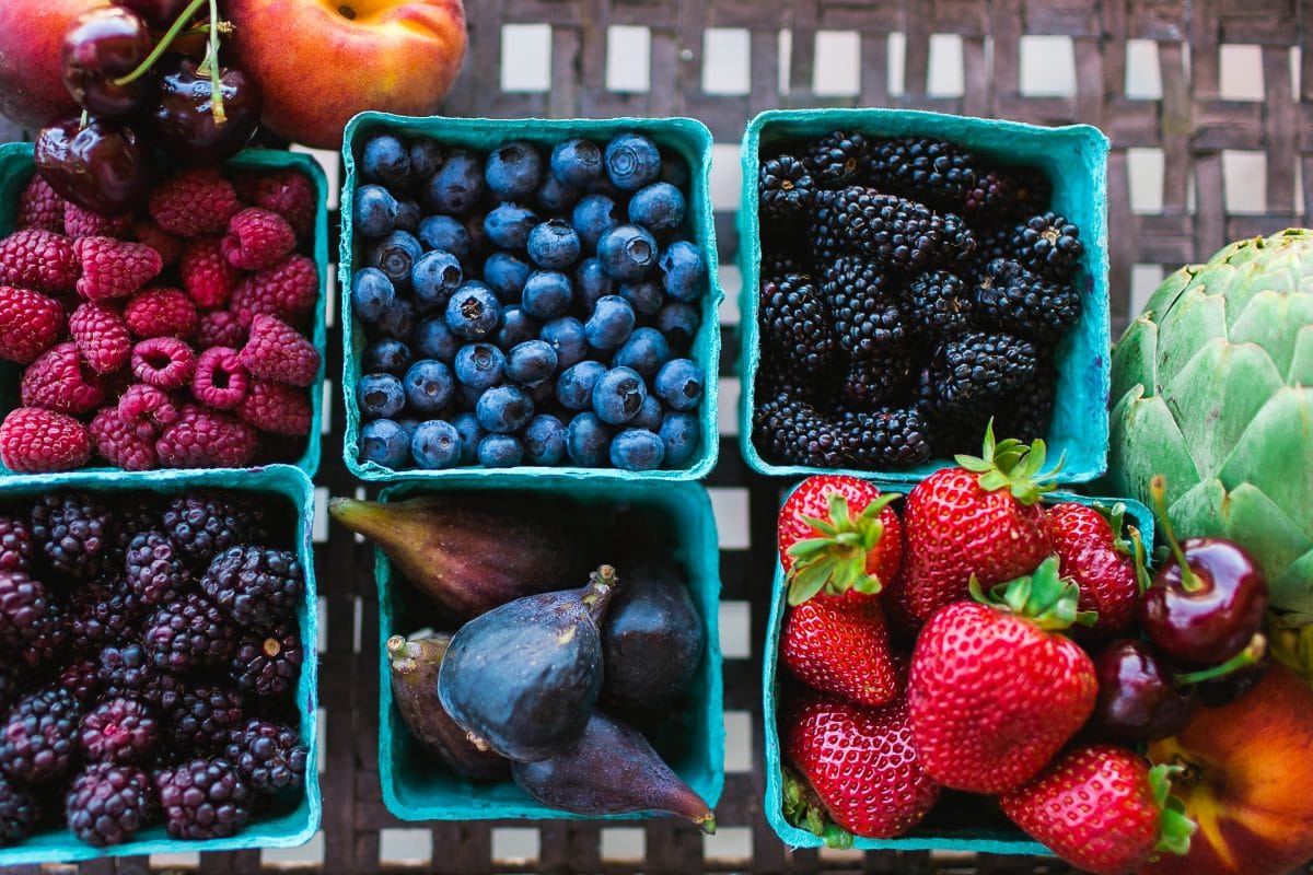 Different berries in blue containers on a table. 