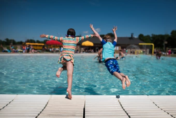Two children jumping into a pool 