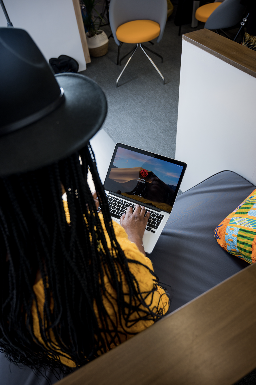 Black woman with braids and a hat on a laptop