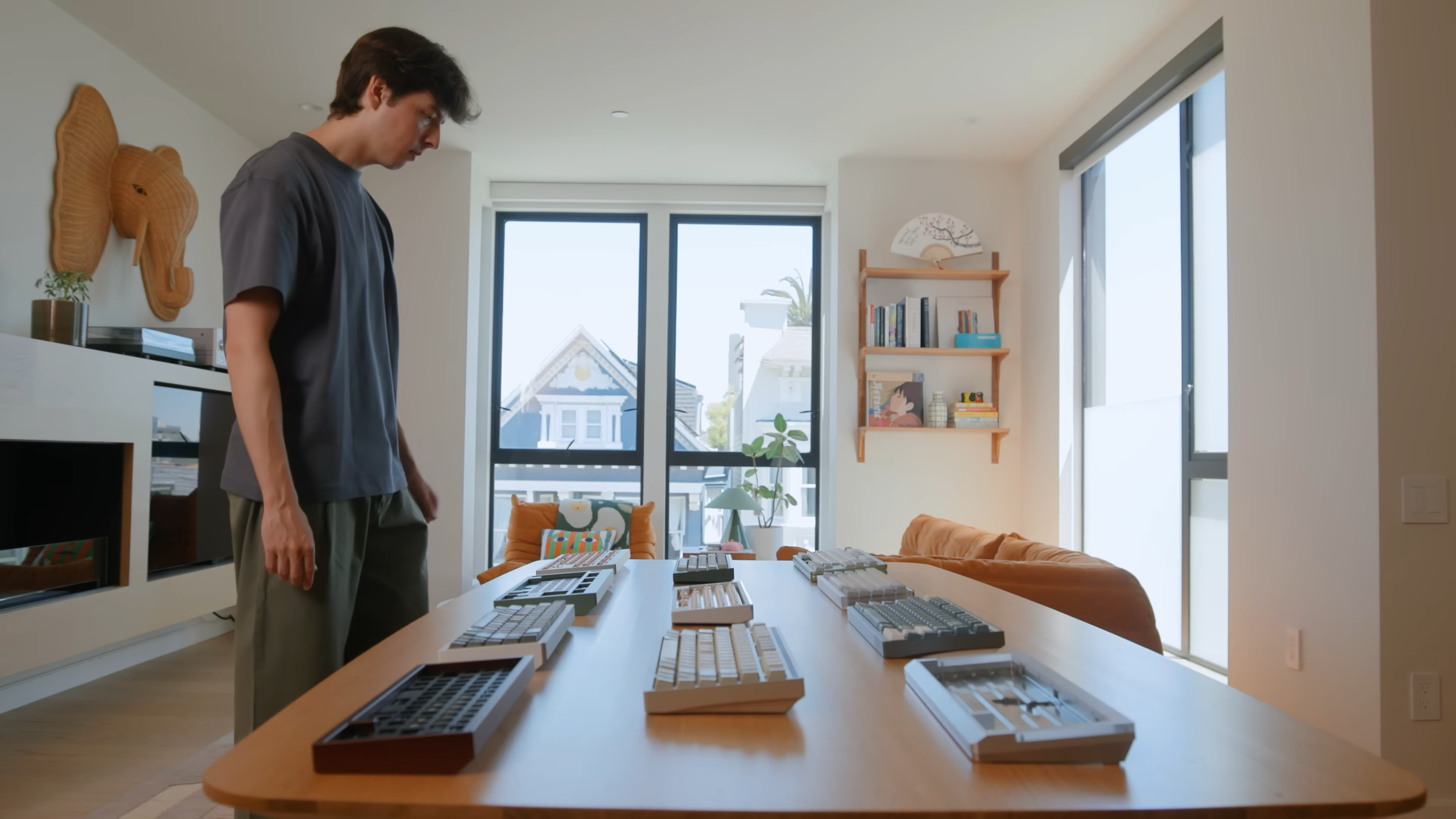 A person stands in a bright, modern living room, thoughtfully looking over a table filled with Mode keyboards. This image introduces the Mode brand and highlights the moment of reflection that sparks the need for a rebrand, as shown in the video.        Ask ChatGPT