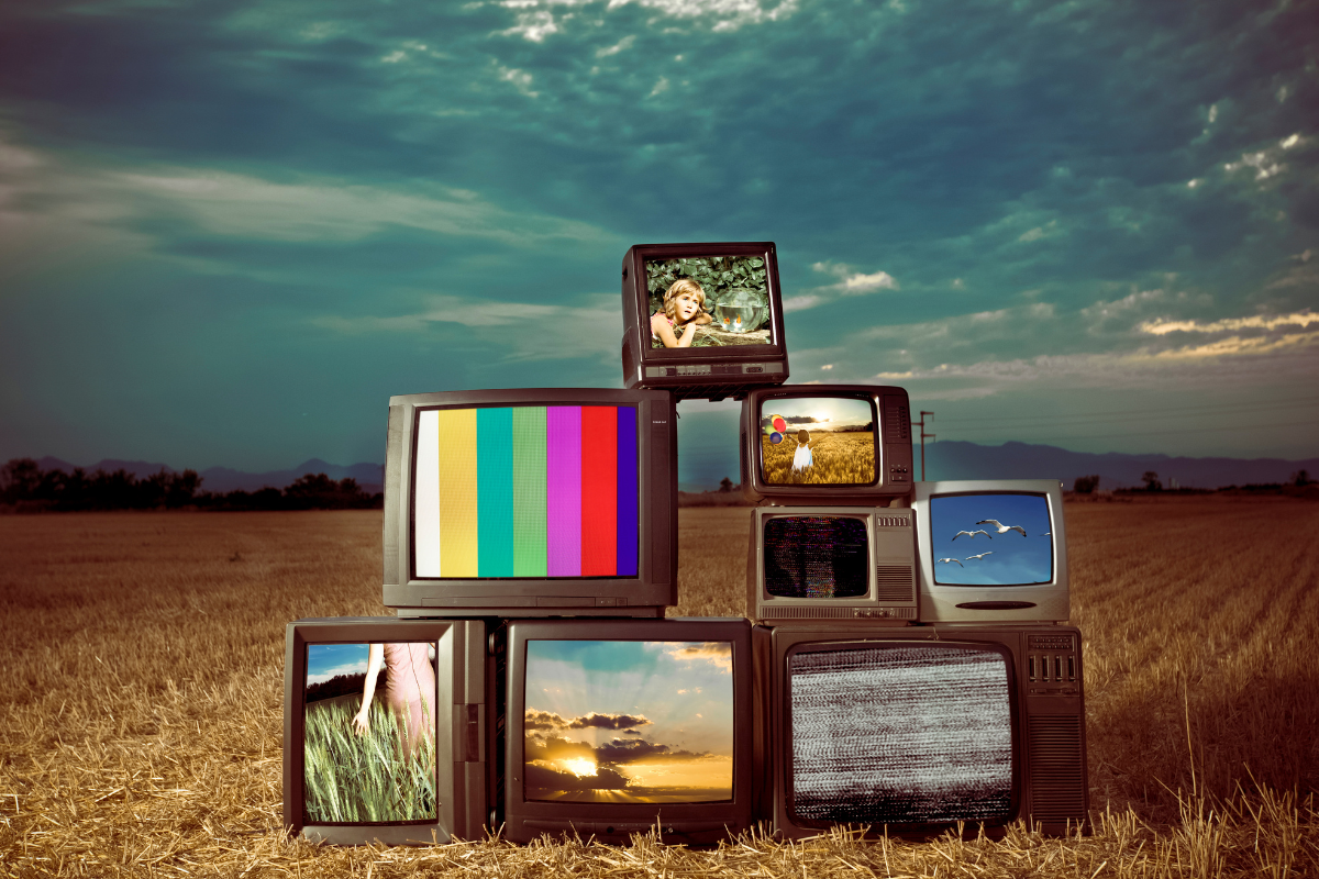 Several Tv sets in an open field with various static images.