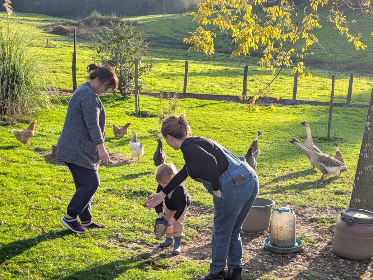 Little girl named Elena feeding chickens at her grandparents’ farm in France, learning about farm animals in French.