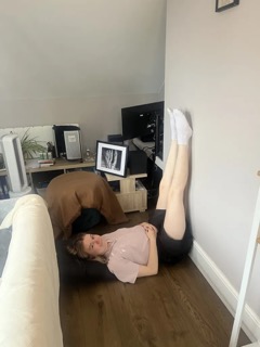 Photo of Esme lying on the floor with her legs up a wall 
