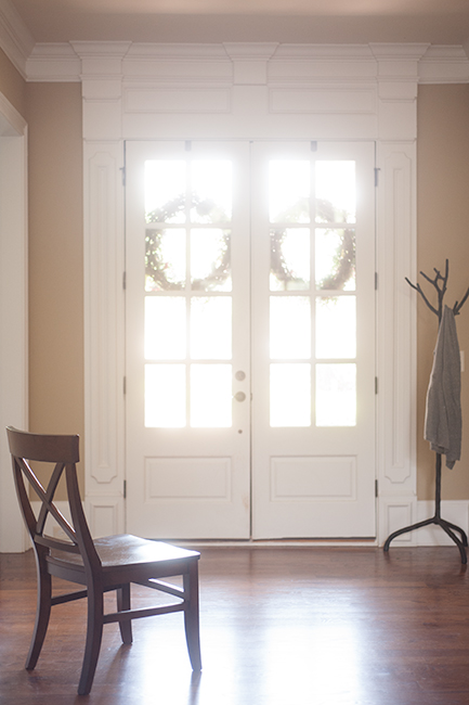 Photo of two white doors with wreaths and the sun coming in from outside.