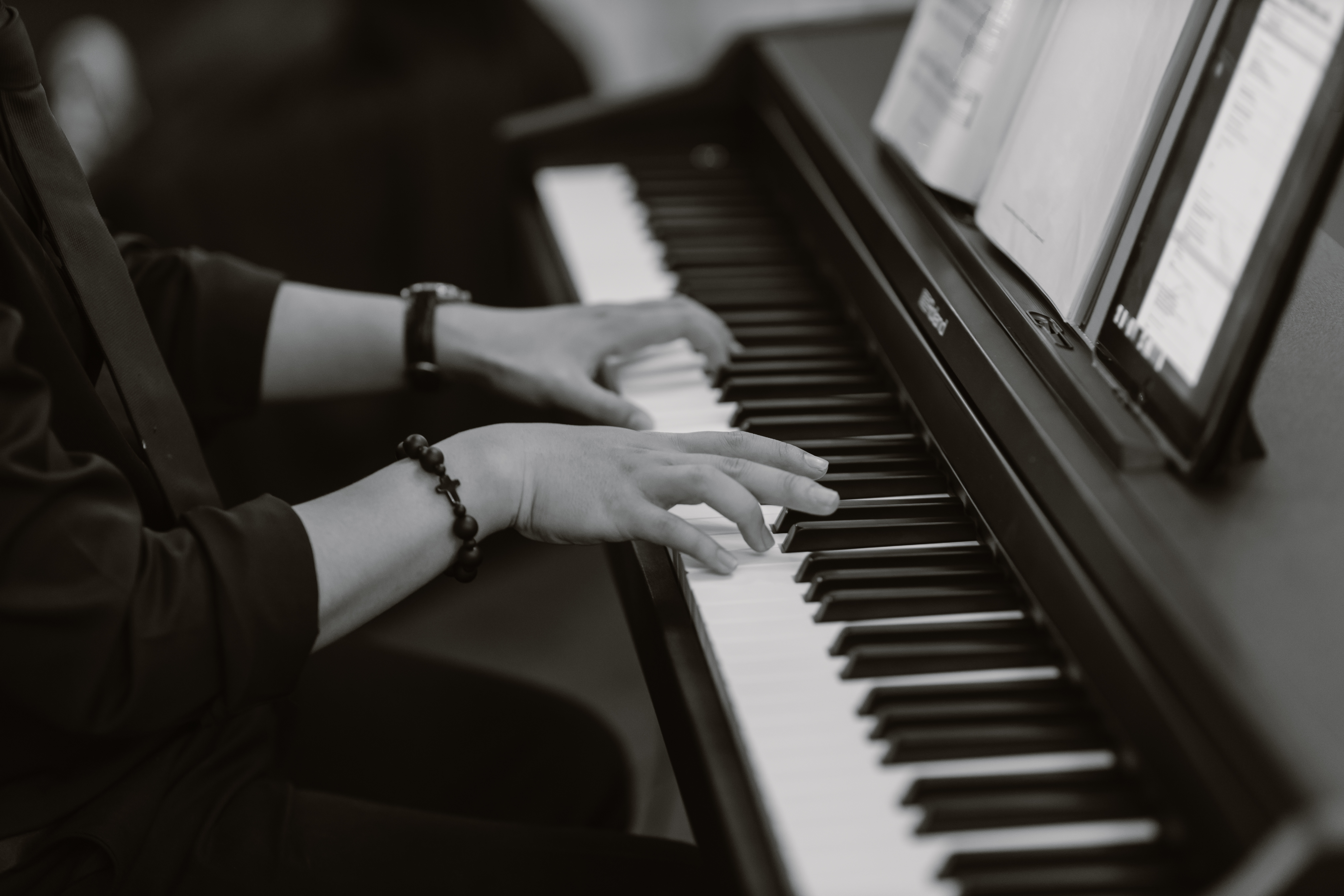 black and white photo of somebody playing piano with a book of music in front of them