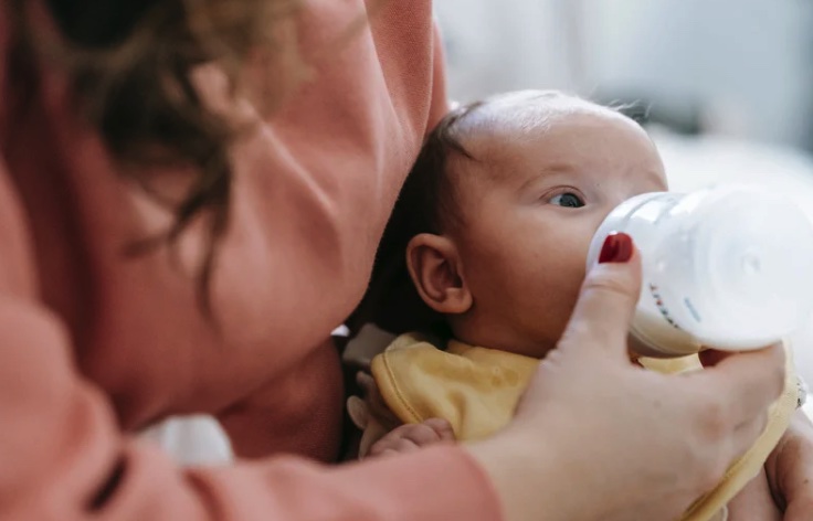 Doula bottle feeding a newborn baby.