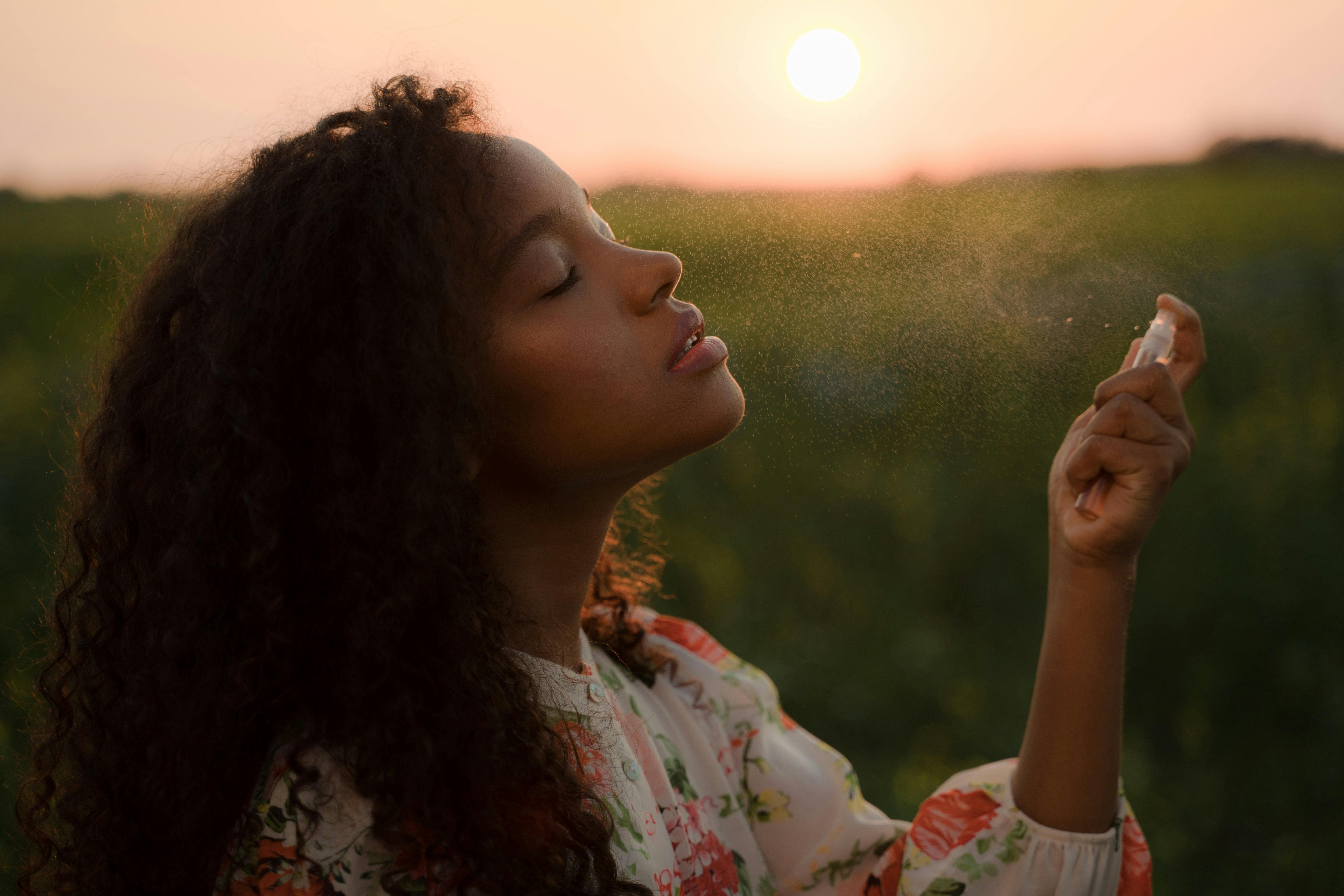 Lady in field with a spray bottle spritzing her face