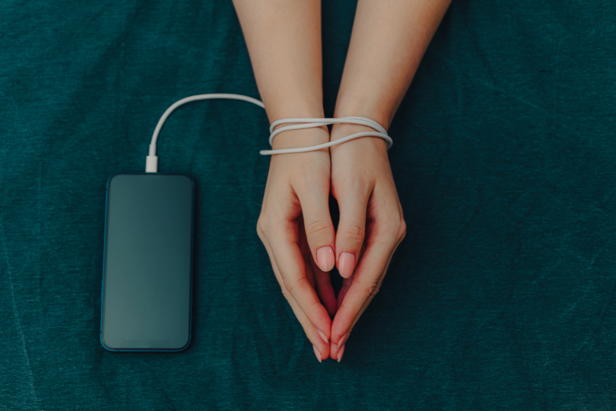 an image of a person's hands tied together by a phone cord, representing the person's enslavement of device. 