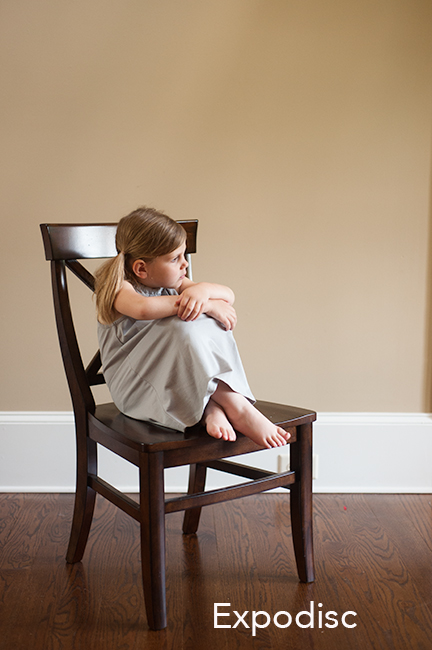 Photo of child sitting in a brown chair using expodisc for white balance.