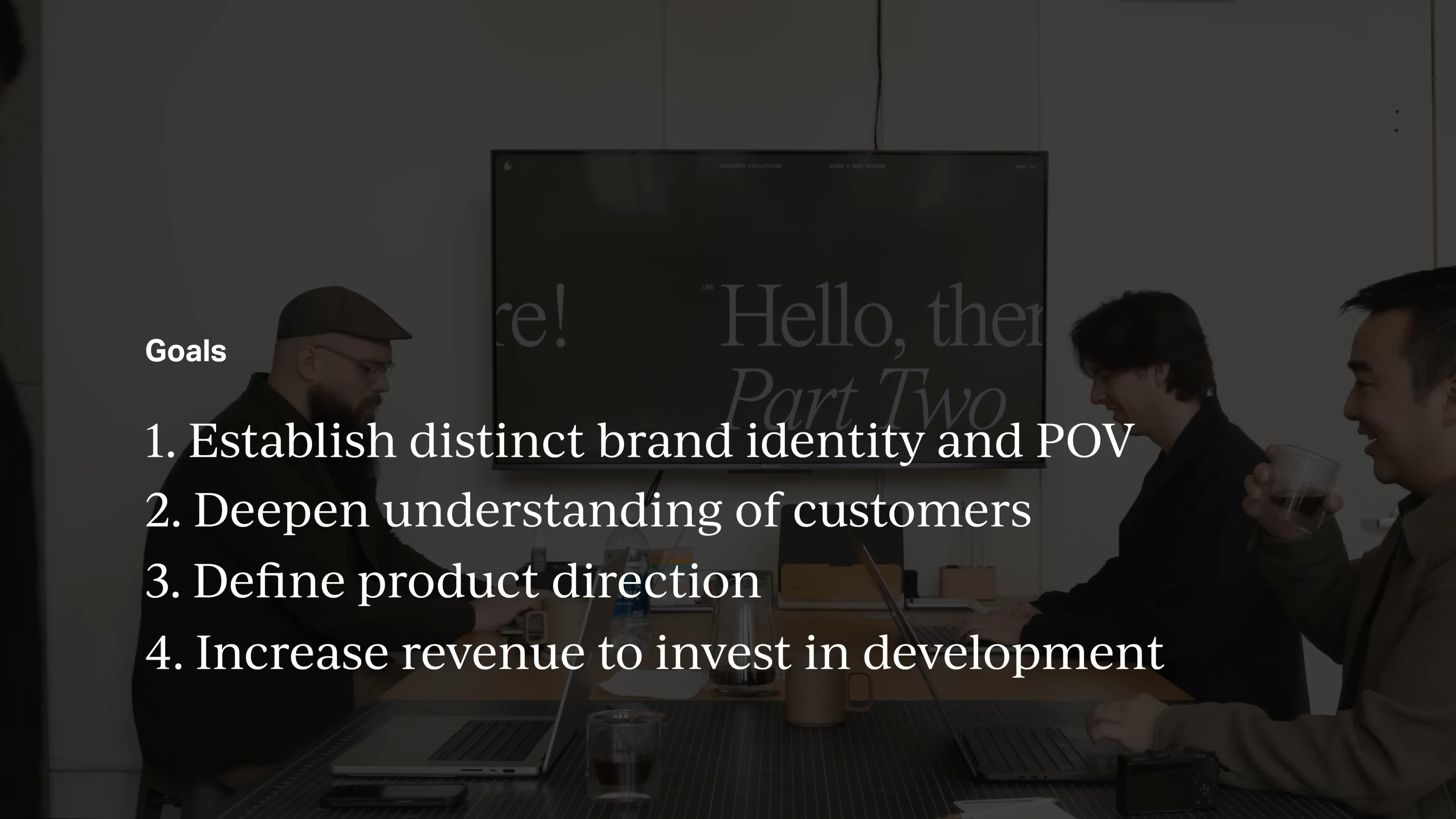 Team meeting discussing key branding goals on screen—establishing brand identity, understanding customers, defining product direction, and increasing revenue—from Matthew Encina’s Mode rebrand video.