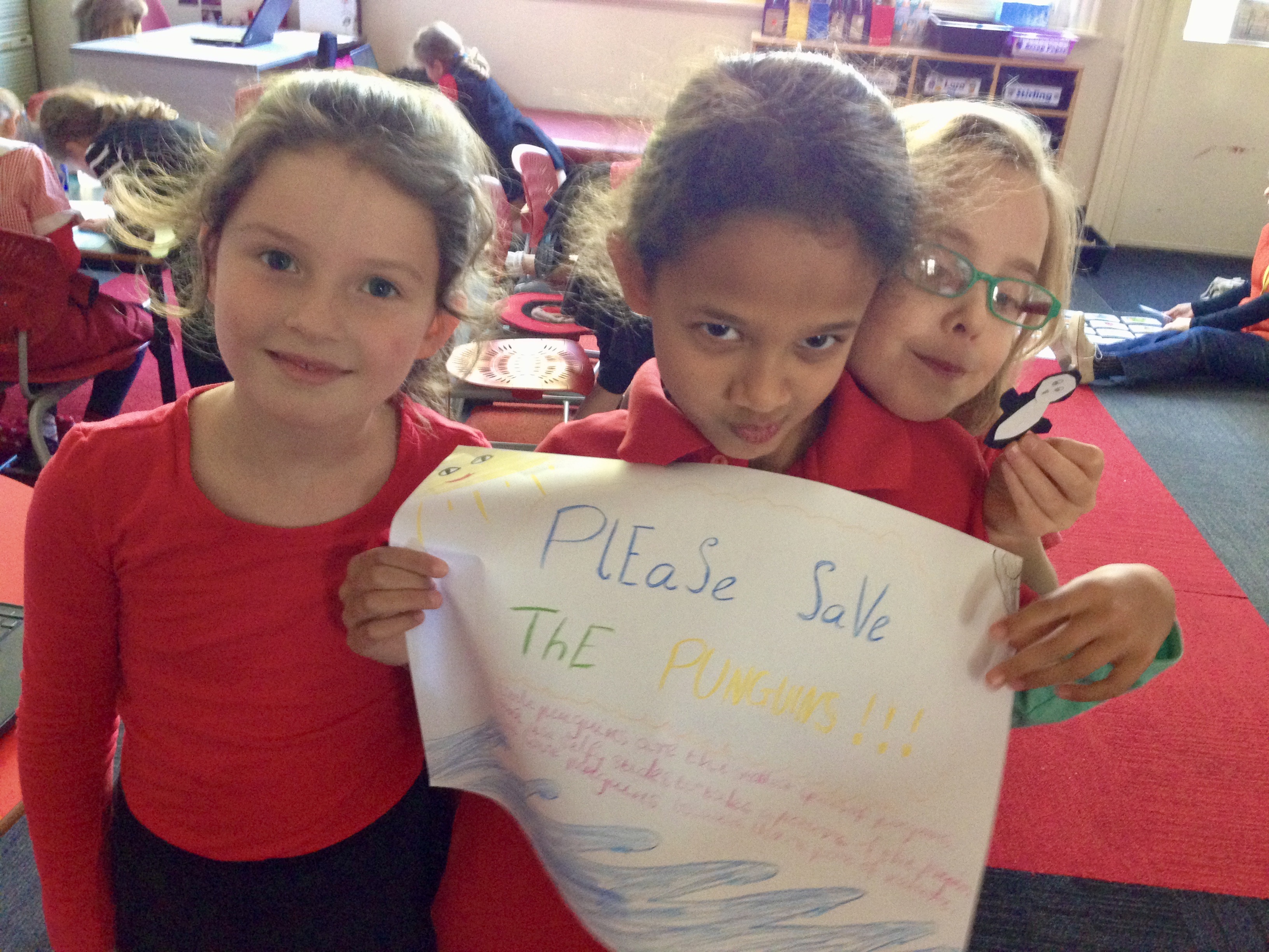Three children holding a poster that says Save the Penguins