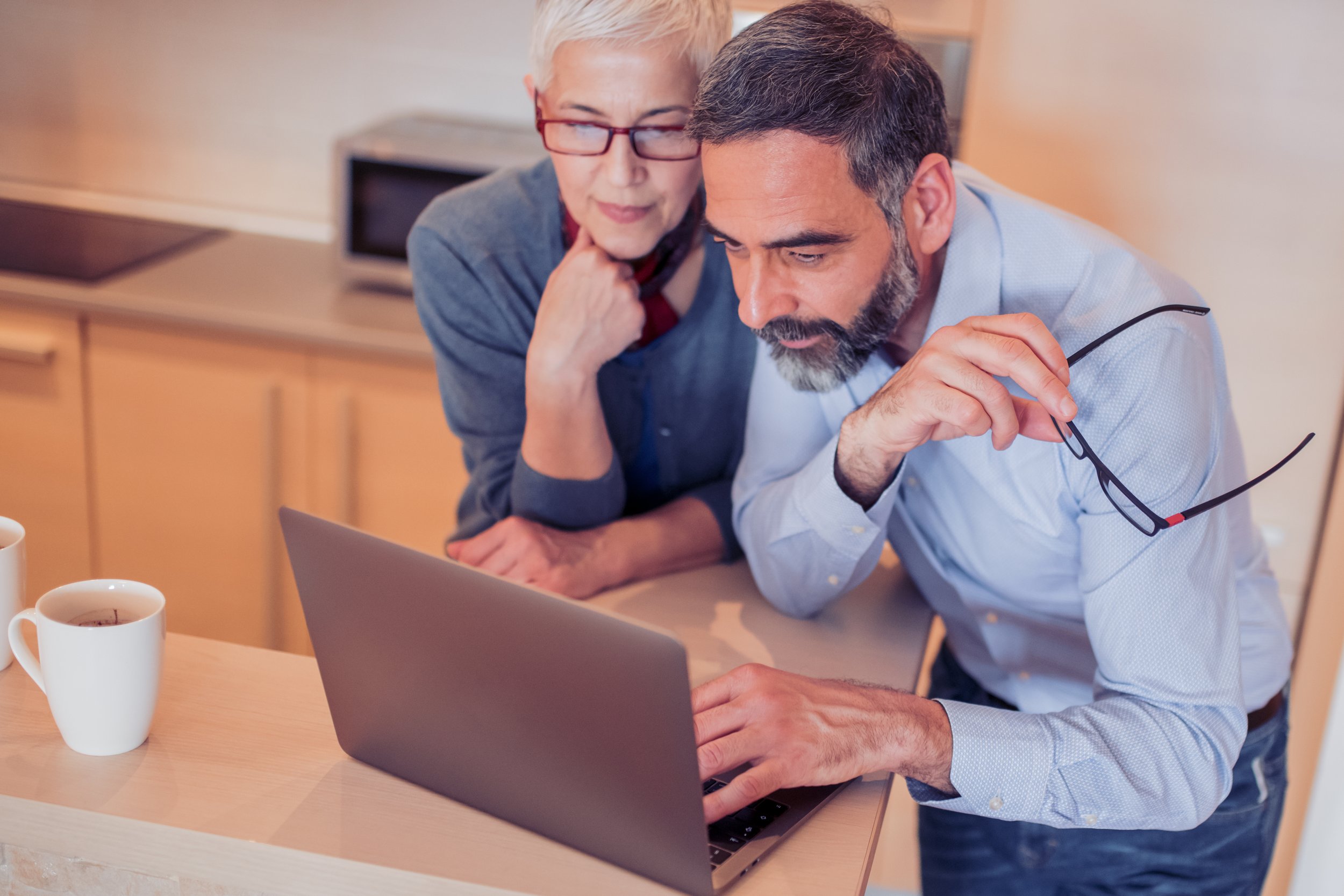 A woman and a man, both in their 50s, looking at a laptop together