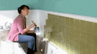 Gif femme qui peint le carrelage de sa salle de bains en blanc et gros plan sur son pinceau