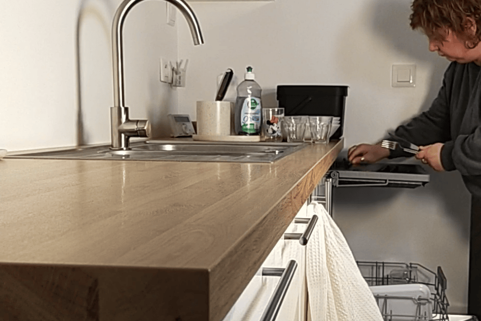 Femme range lave-vaisselle cuisine - action immédiate arrêter procrastination tâches ménagères organisation maison routine home organiser