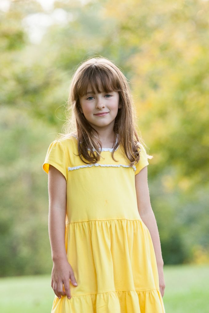 Child in yellow dress with a soft glow behind her from backlight photography