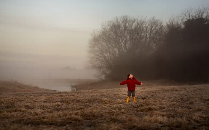 child in red coat in field of fog for minimalist photo