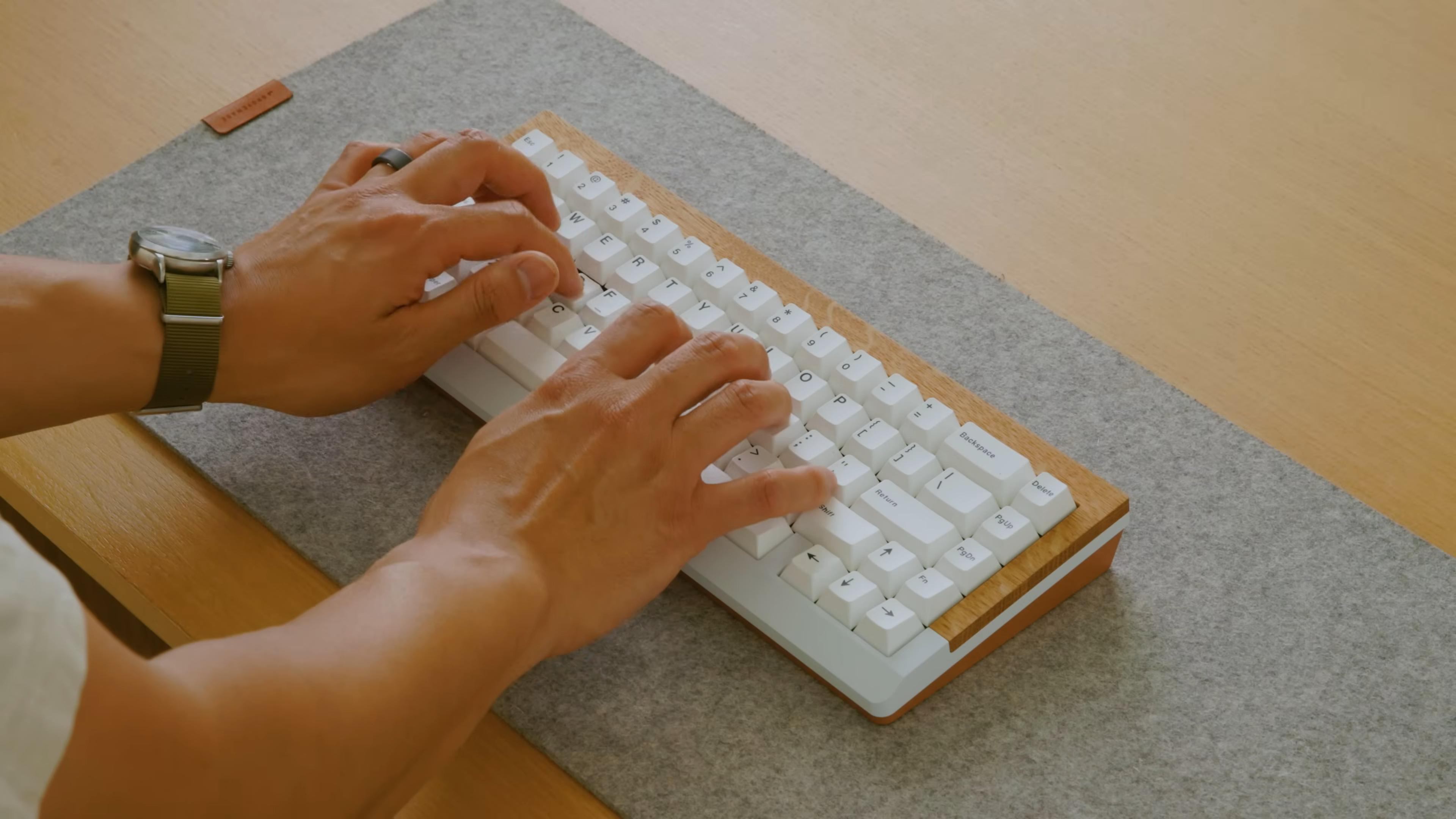 Hands typing on a Mode mechanical keyboard with a wood accent, as seen in Matthew Encina’s video on rebranding a business.