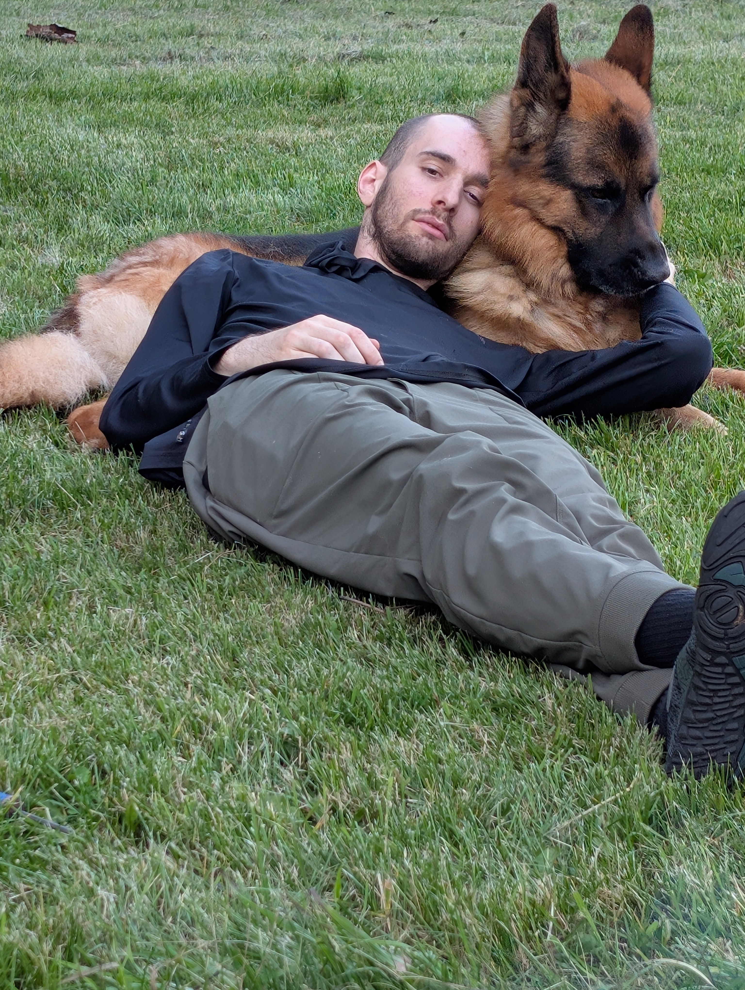 a boy and his german shepherd resting in the grass