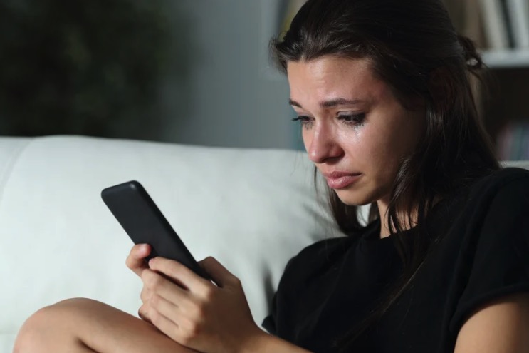 woman looking at phone crying