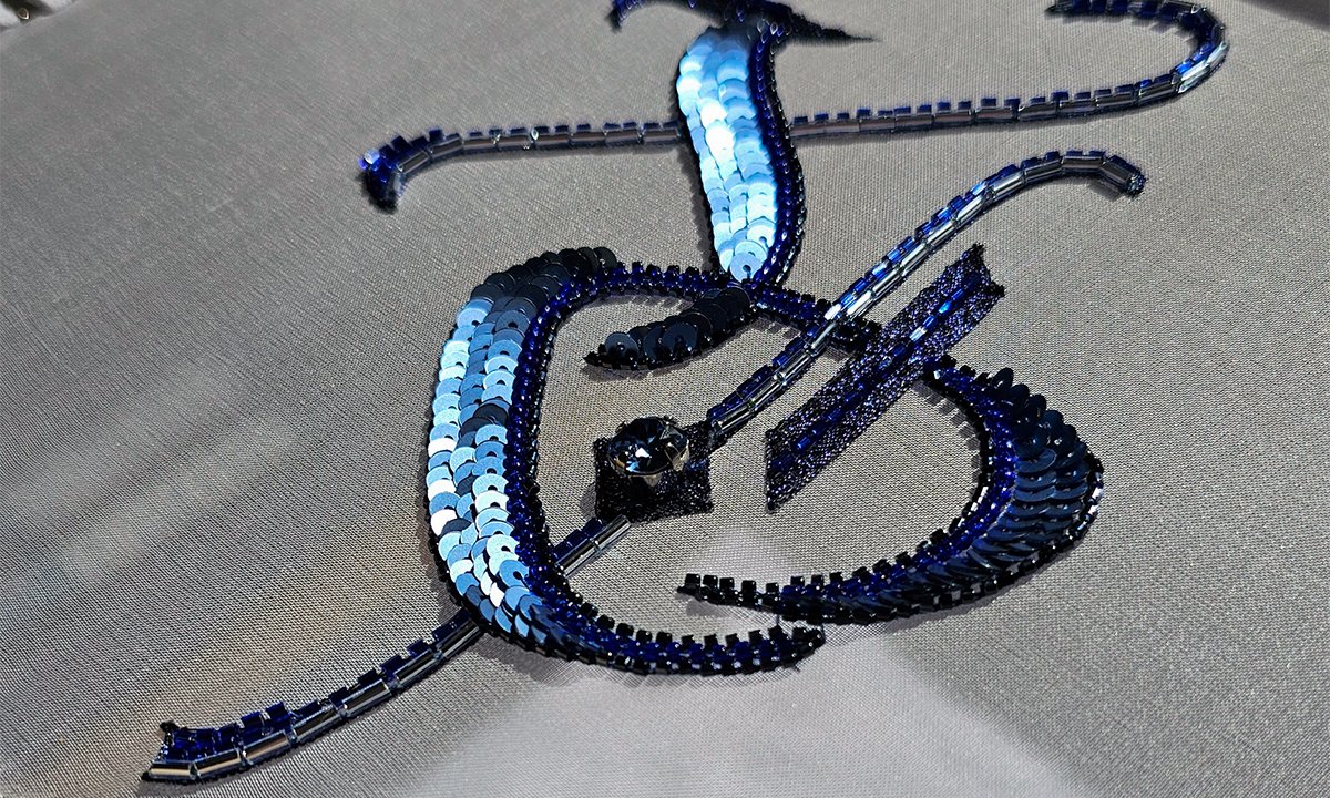 Final XO composition stitched with Luneville embroidery techniques using sequins, bugle beads, and rhinestones on organza.