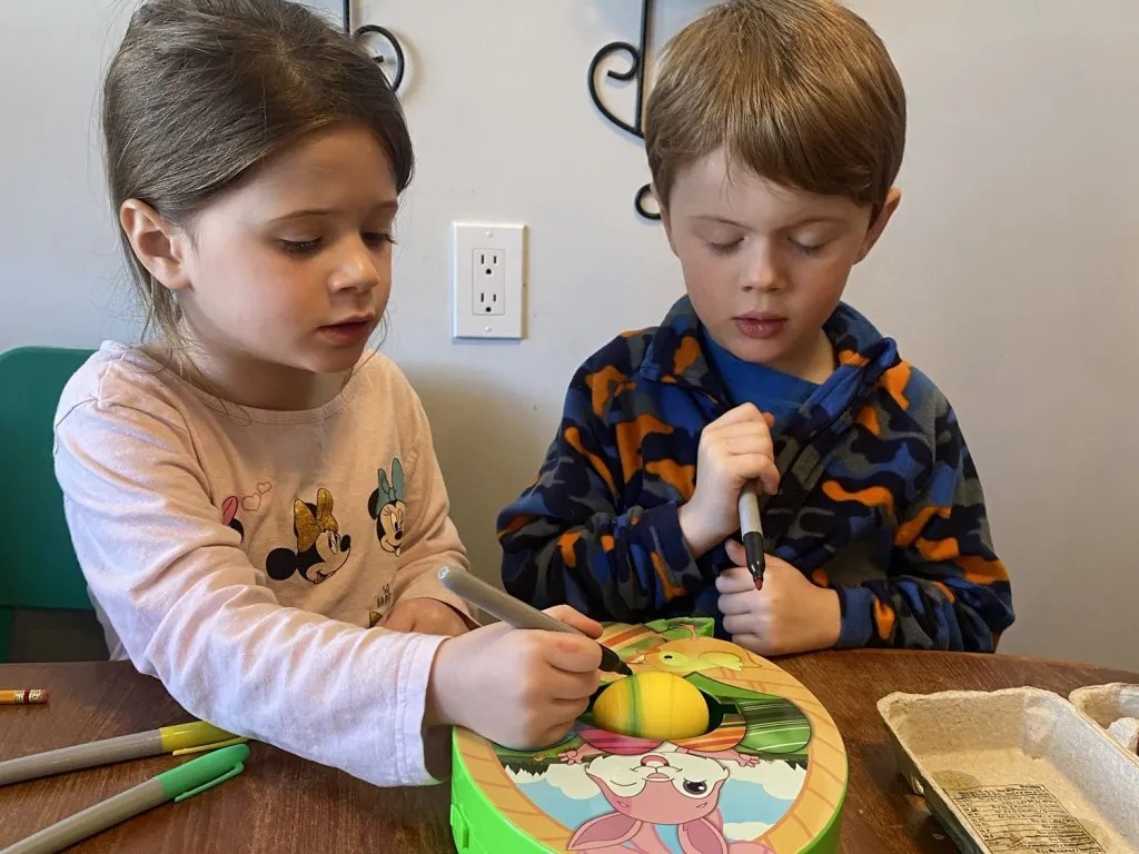 twin siblings creating colored easter eggs