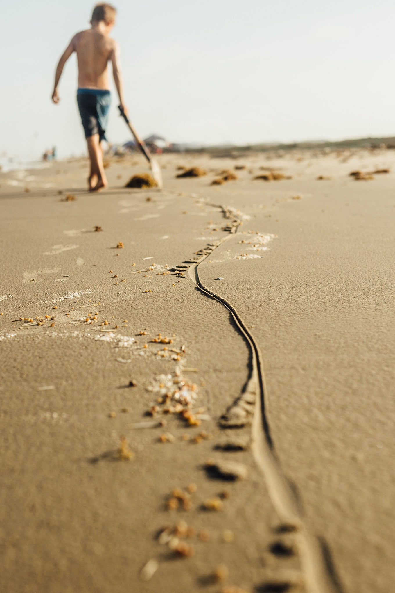 Child drawing in the sand with a shovel