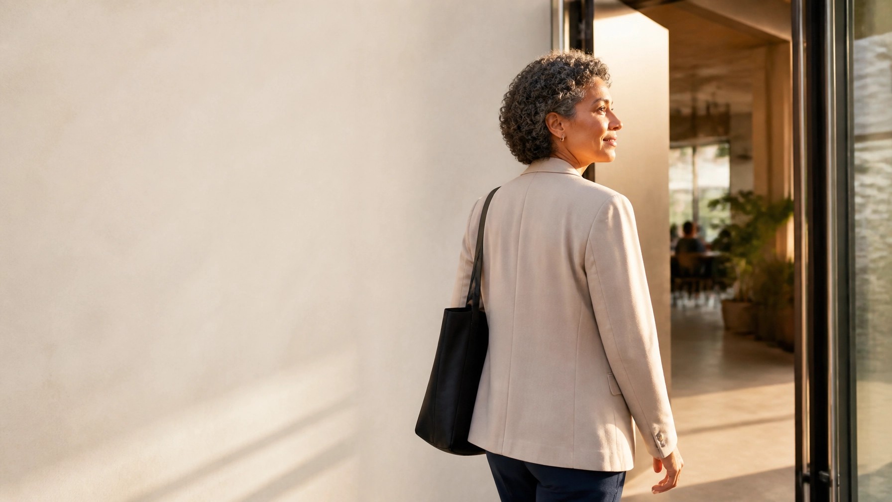  Professional woman walking confidently toward a bright doorway and a new chapter.