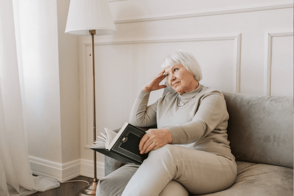 Femme senior lisant calmement dans son salon, symbole d’un intérieur apaisé et adapté pour bien vivre chez soi plus longtemps