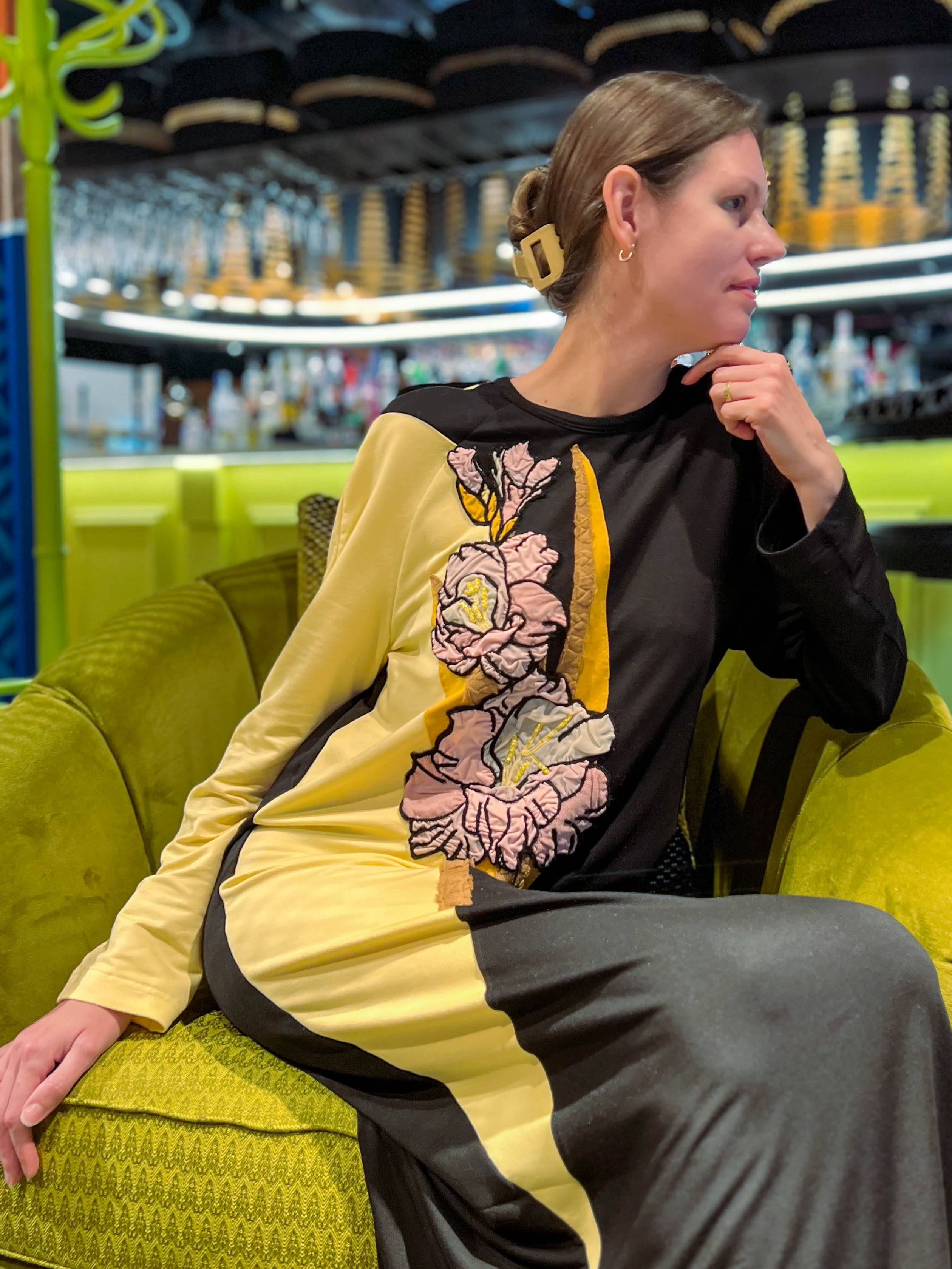 Woman wearing a black and yellow dress featuring a large gladiolus-inspired floral appliqué; an example of contemporary contrast-based embellishment used in the Gladiolus course.