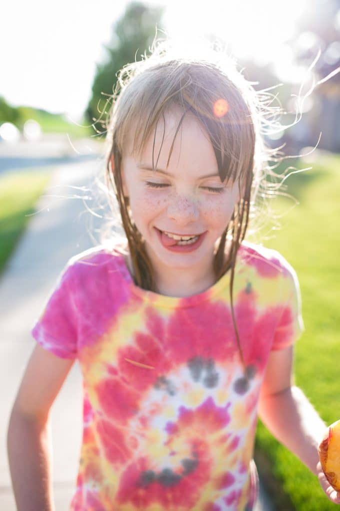 Child in front of the sun making a silly face with a sun flare and the use of backlighting photography.