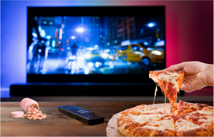 Someone eating pizza in front of the TV with a bottle of Tums spilled out.